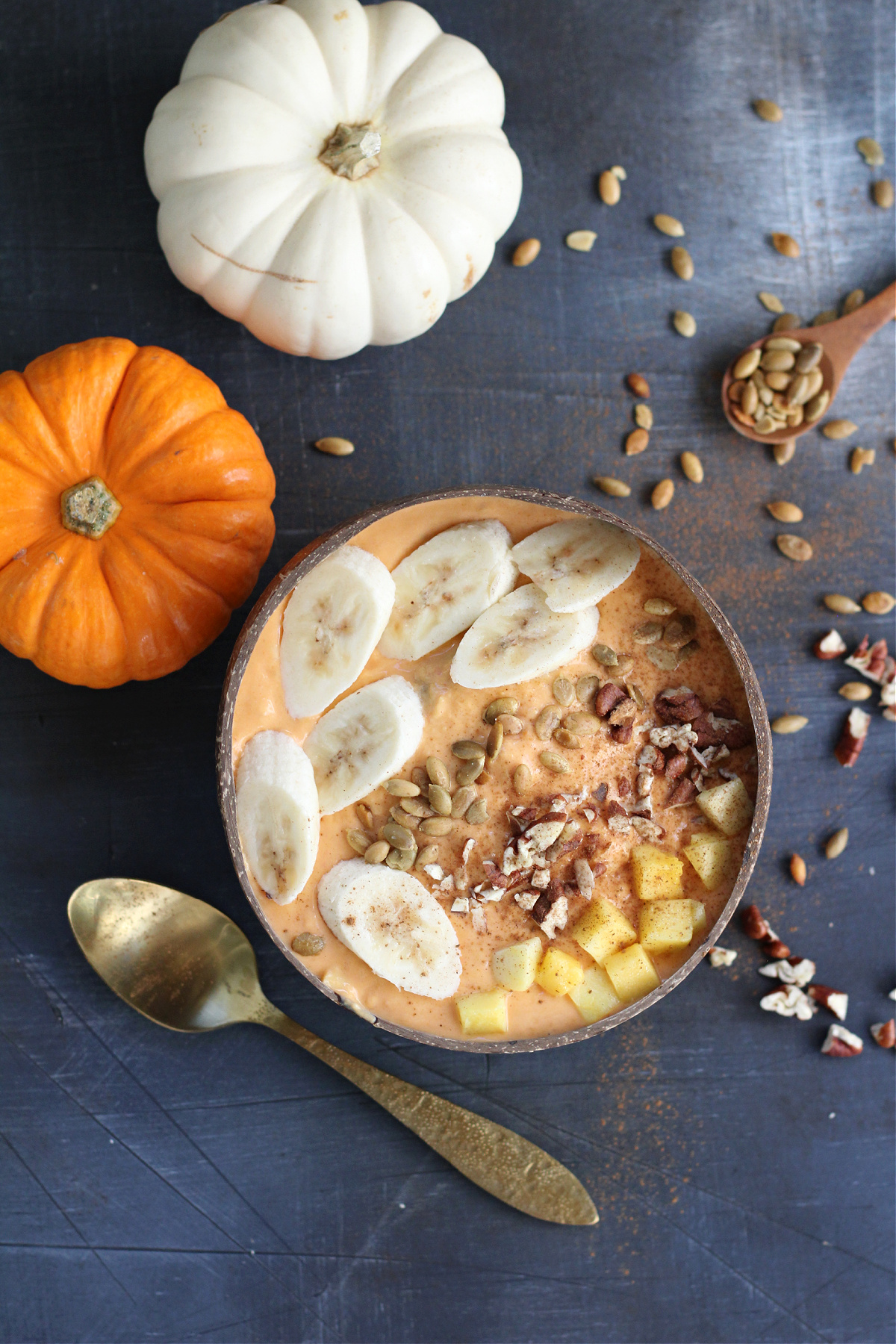 Healthy fall smoothie bowl with pumpkin, mango, and watermelon served in a coconut bowl with fresh banana slices