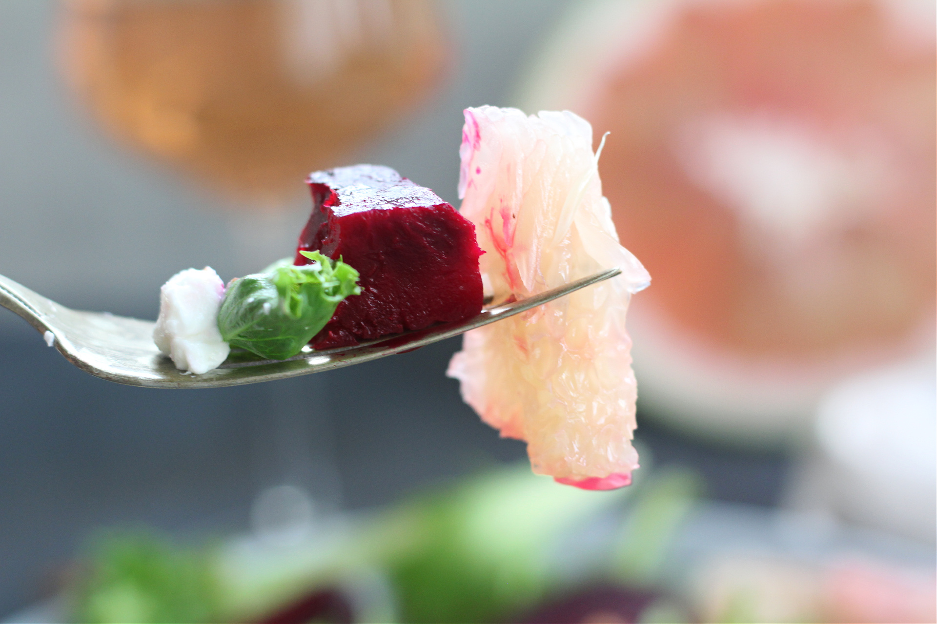 Healthy roasted beet and citrus salad topped with pummelo segments on a fork