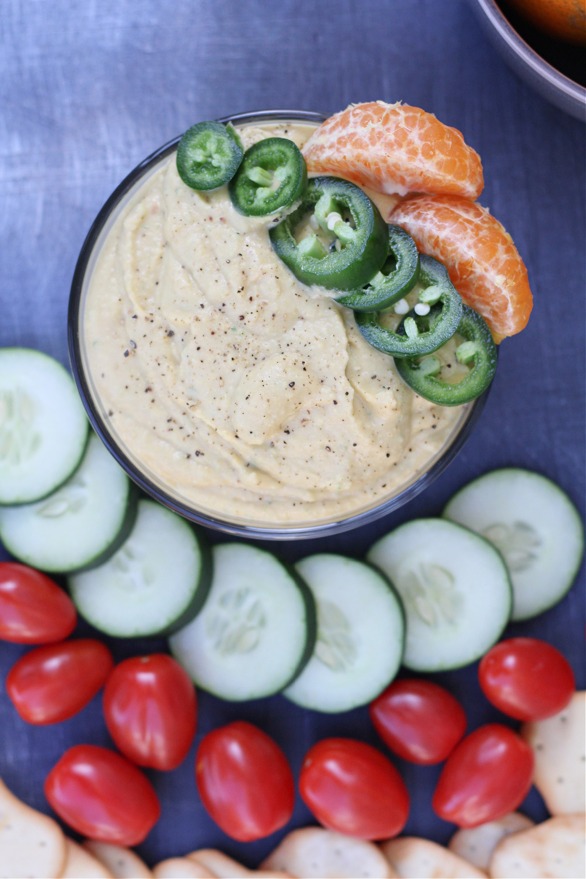 Bowl of homemade spicy tangerine hummus topped with jalapeno and tangerine slices served with fresh veggies Bowl of homemade spicy tangerine hummus topped with jalapeno and tangerine slices served with fresh veggies