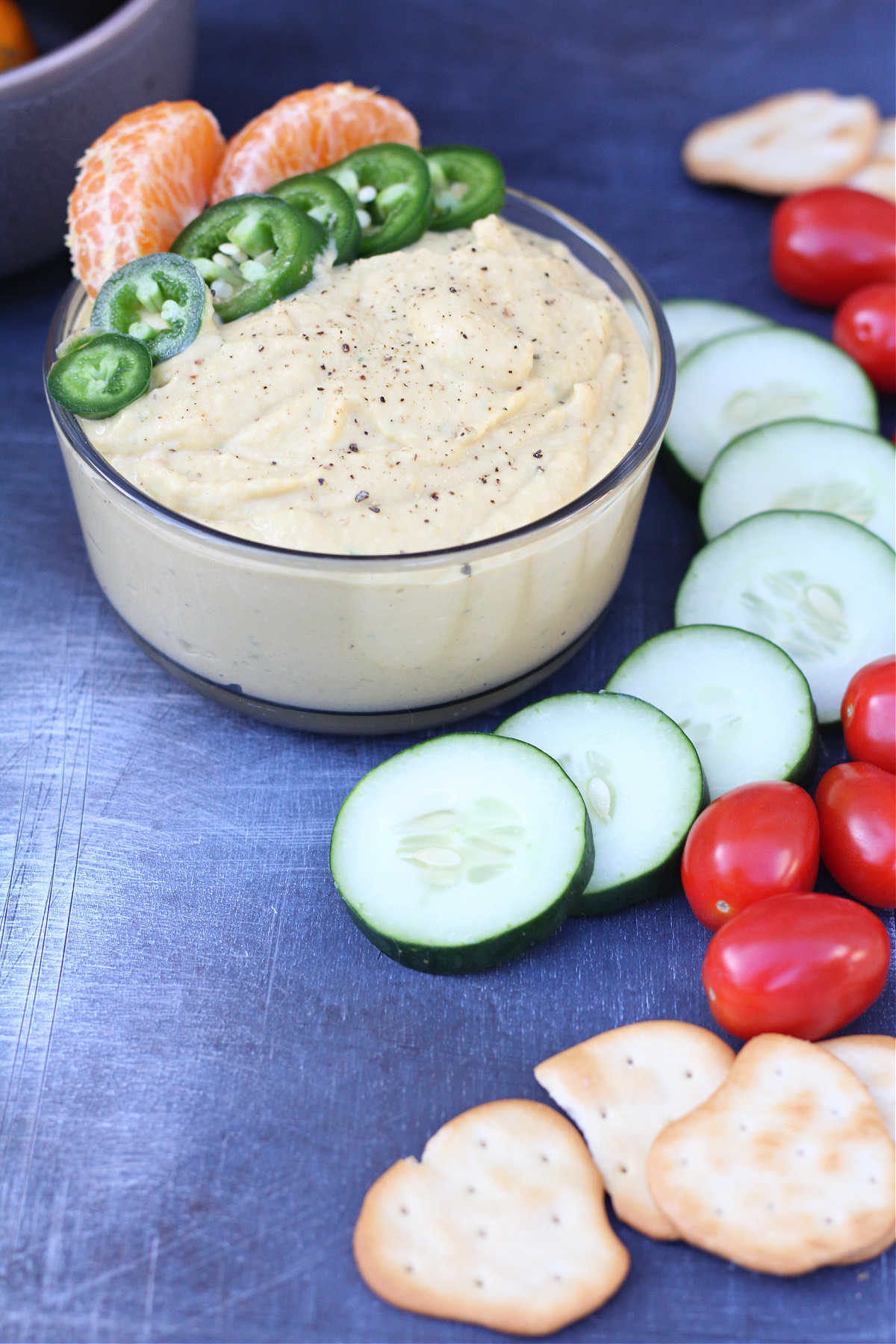 Spicy citrus hummus served on a board with crackers and colorful vegetables. Spicy citrus hummus served on a board with crackers and colorful vegetables.
