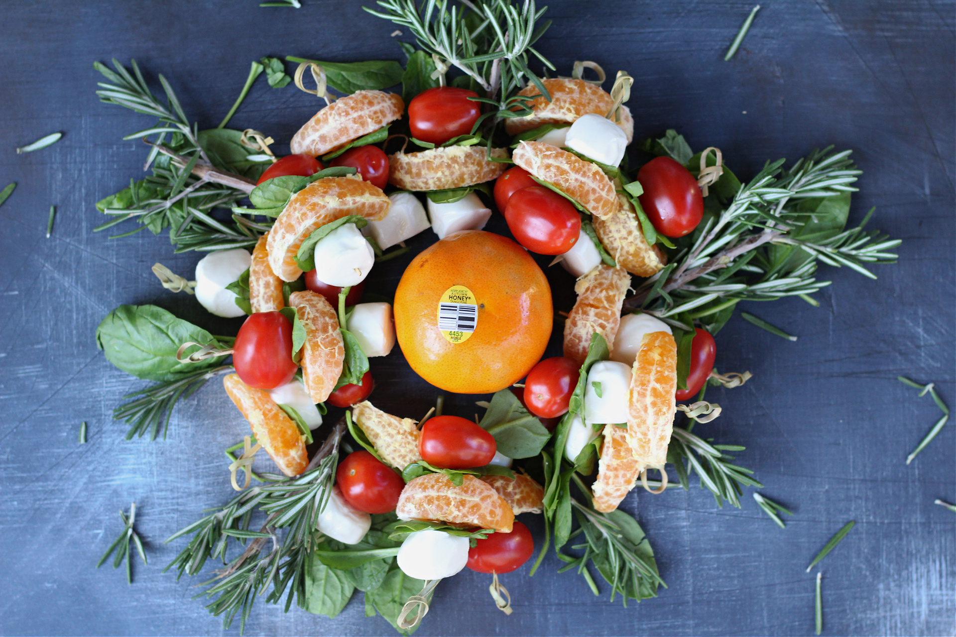 Colorful holiday appetizer featuring tangerine segments, mozzarella pearls, and baby spinach.