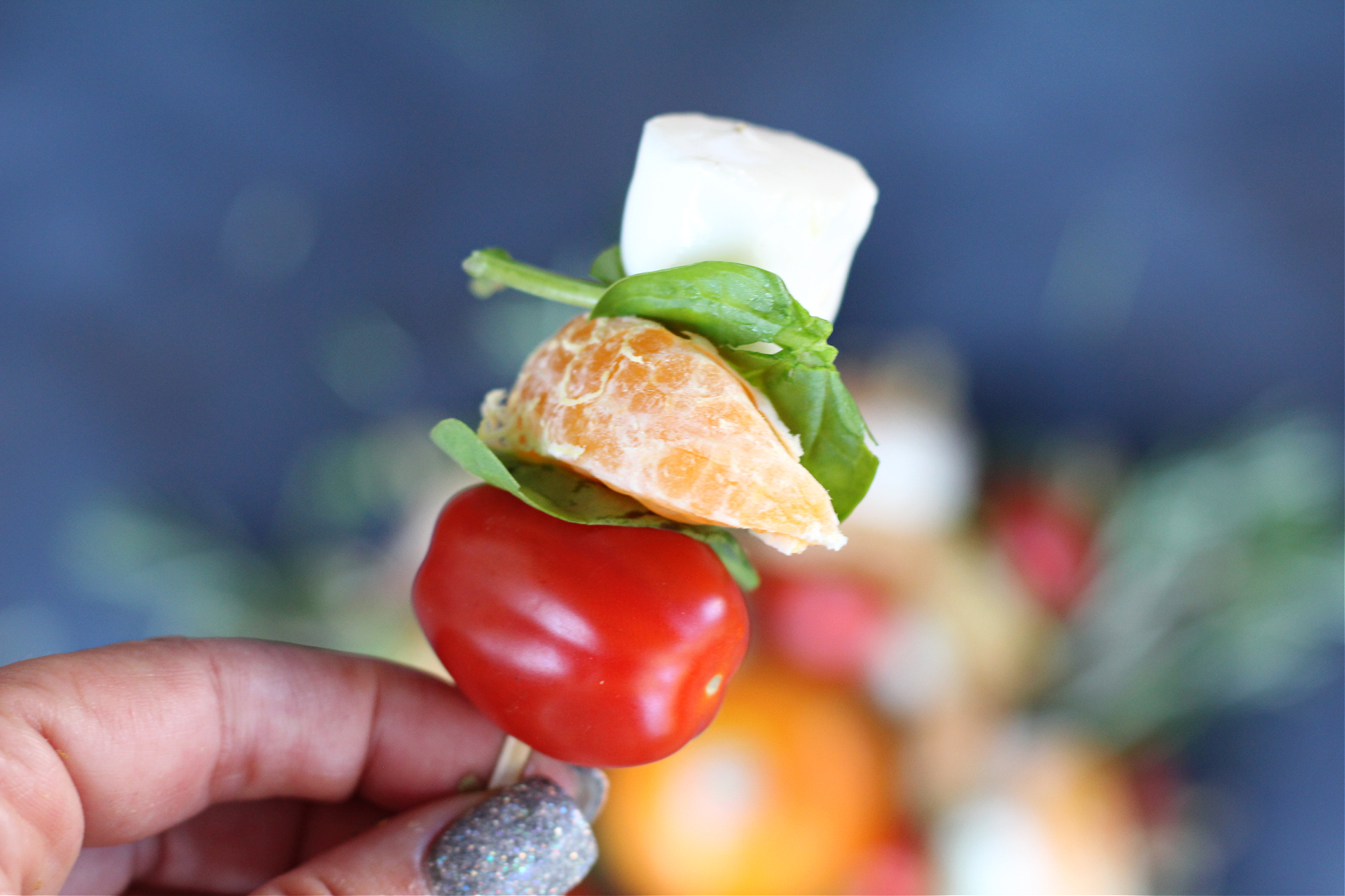 Close-up of tangerine, mozzarella, and tomato skewers on bamboo toothpicks.