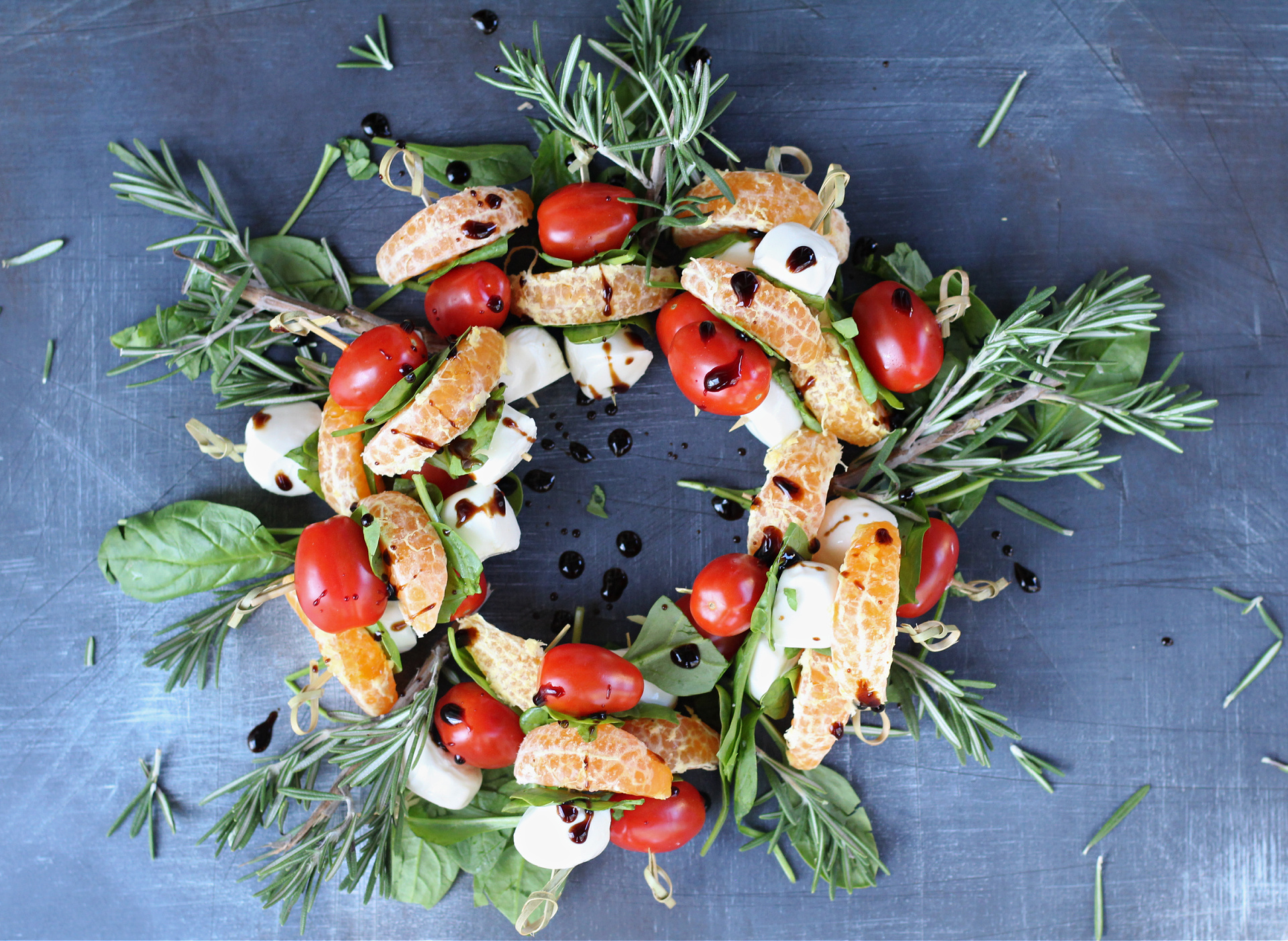 Festive caprese kabobs drizzled with balsamic glaze on a serving platter.