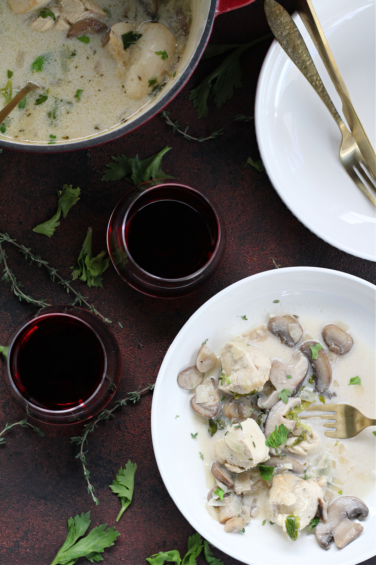 Close-up of chicken and mushroom fricassee in creamy sauce served in a white bowl paired with red wine
