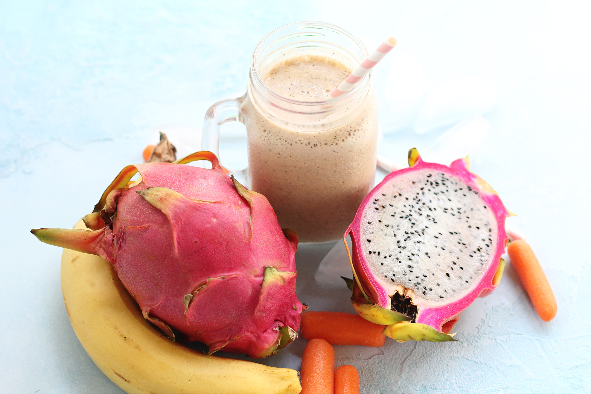 Dragon fruit smoothie in a clear glass with tropical fruit.