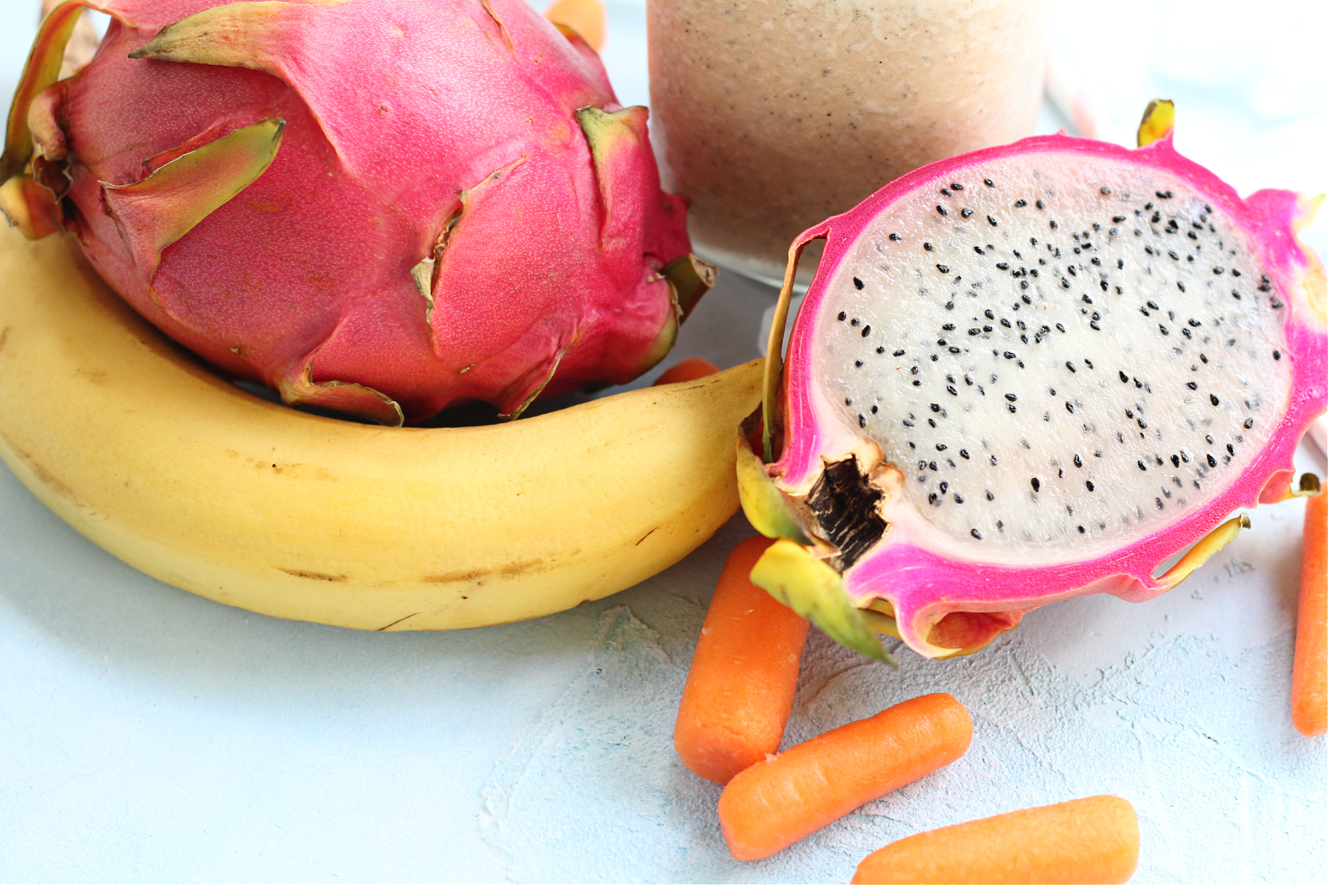 Close up of the inside of a dragon fruit with a dragon fruit smoothie in the background.