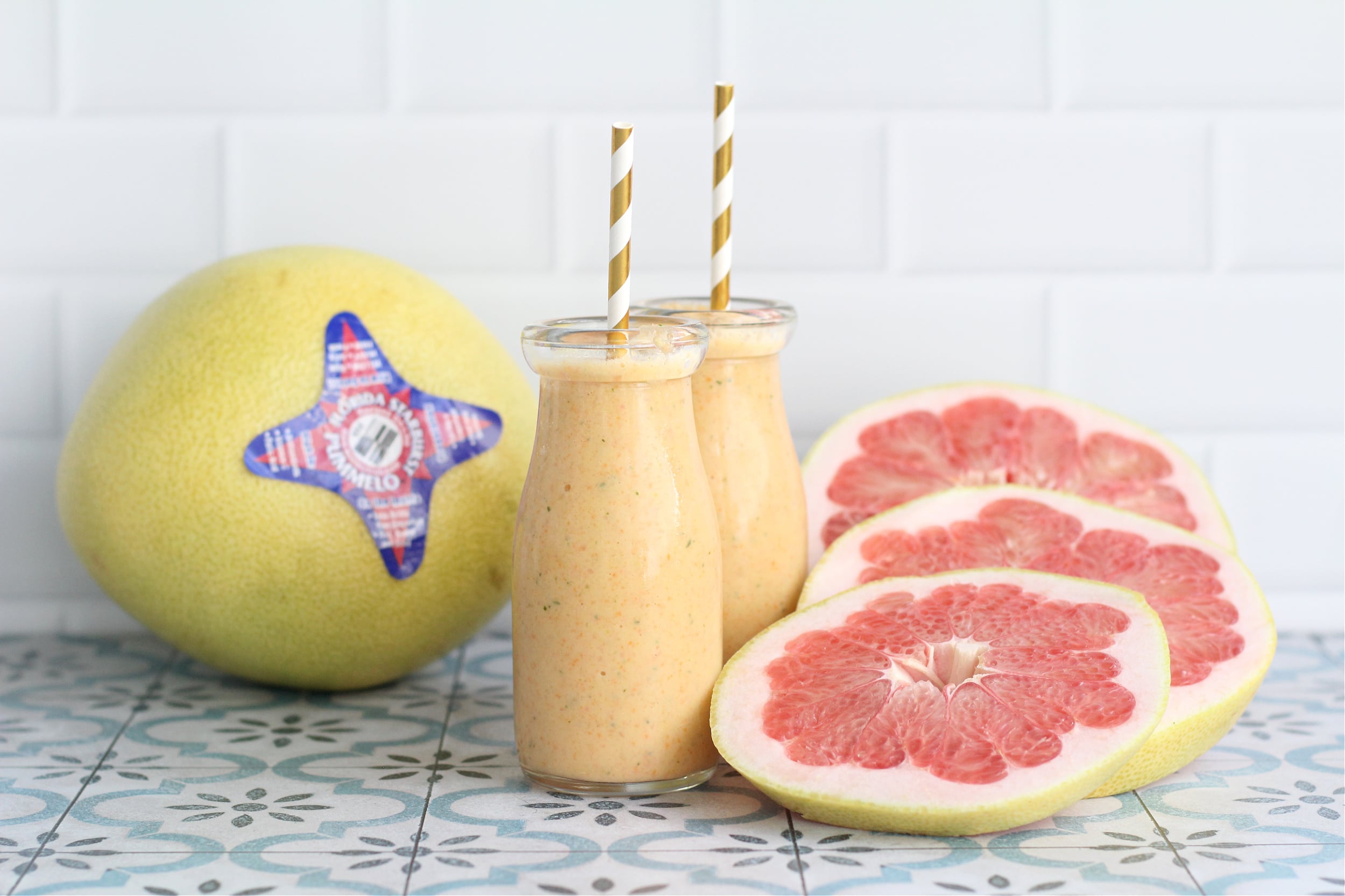 Citrus smoothie with gold straws in the glasses with an pummelo slices and a whole pummelo in the background. Citrus smoothie with gold straws in the glasses with an pummelo slices and a whole pummelo in the background.