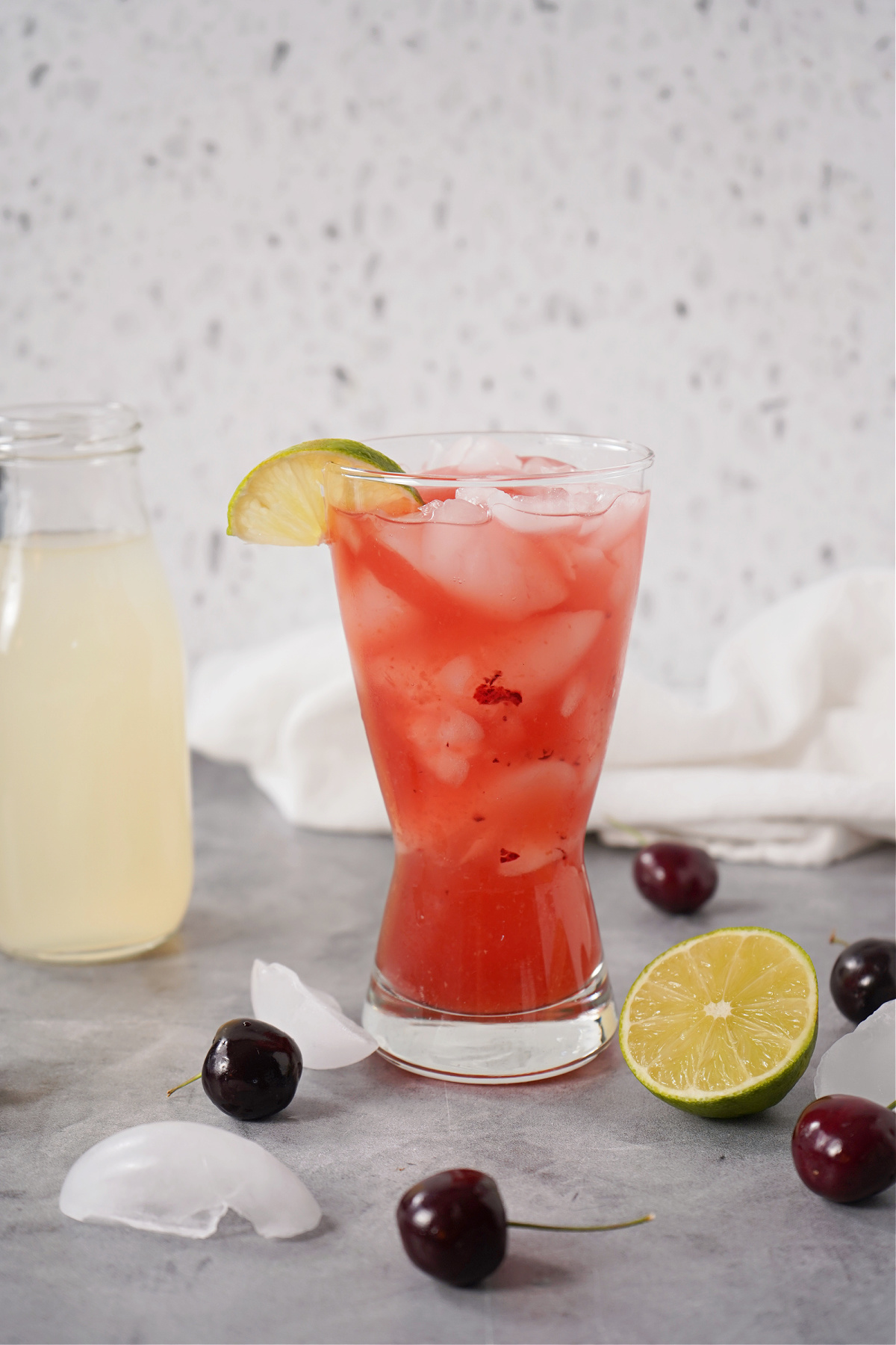 Summer drink scene featuring a cherry spritz, cherries, and citrus on a countertop.
