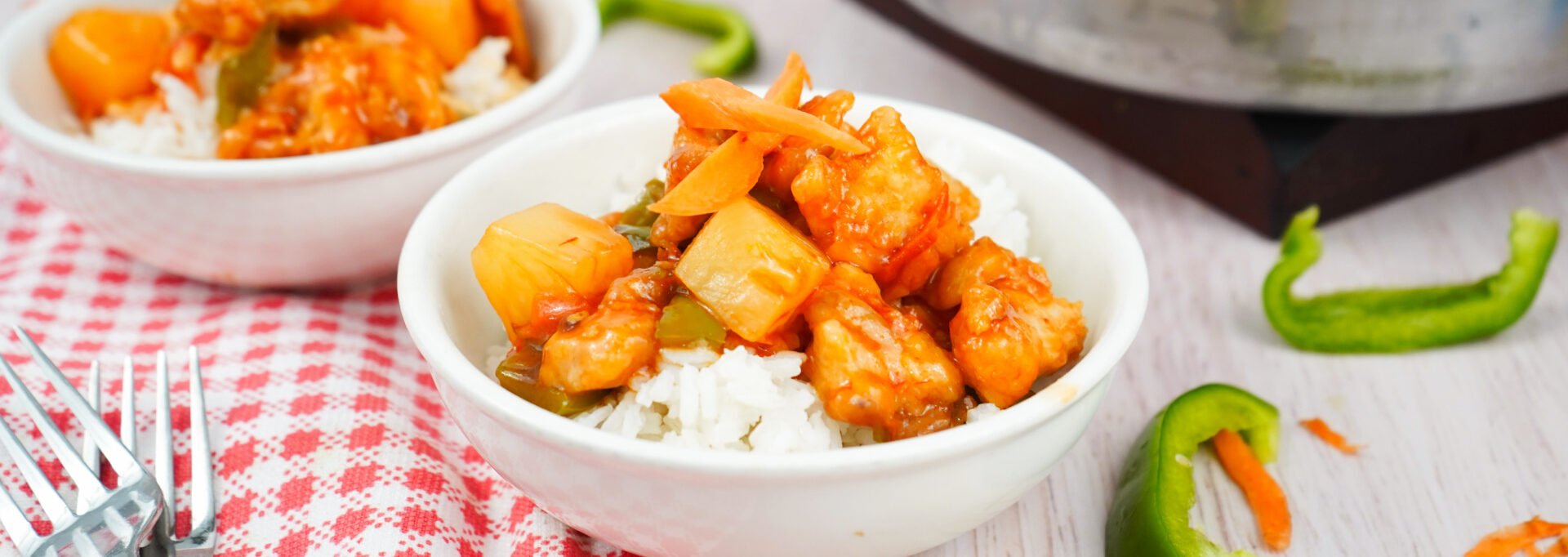 Bowl of homemade sweet and sour chicken with pineapple and vegetables served over white rice.