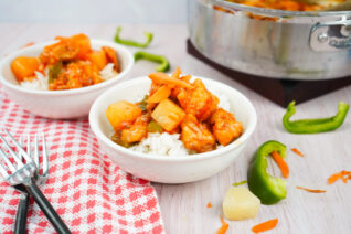 Bowl of homemade sweet and sour chicken with pineapple and vegetables served over white rice.