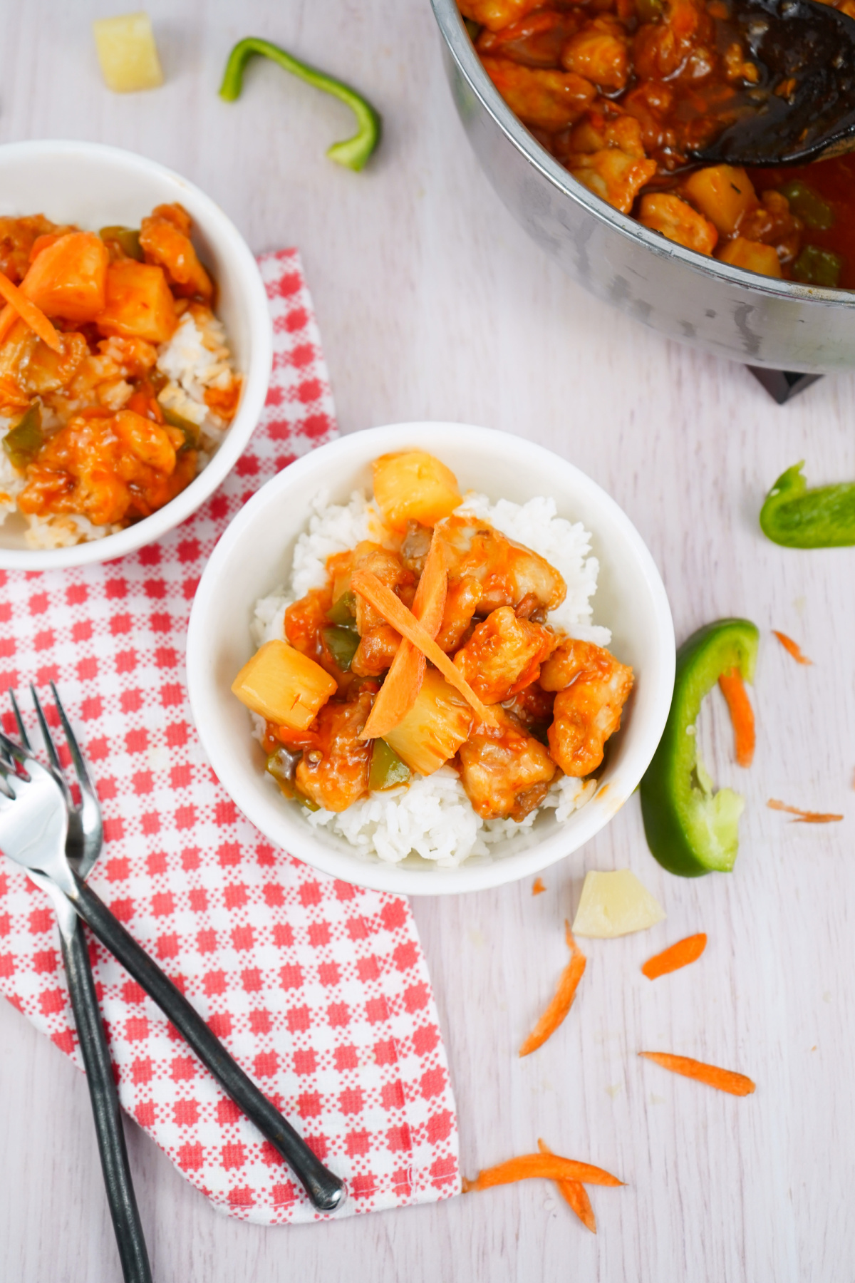 Overhead view of sweet and sour chicken in a white bowl with rice, ready to eat. Overhead view of sweet and sour chicken in a white bowl with rice, ready to eat.