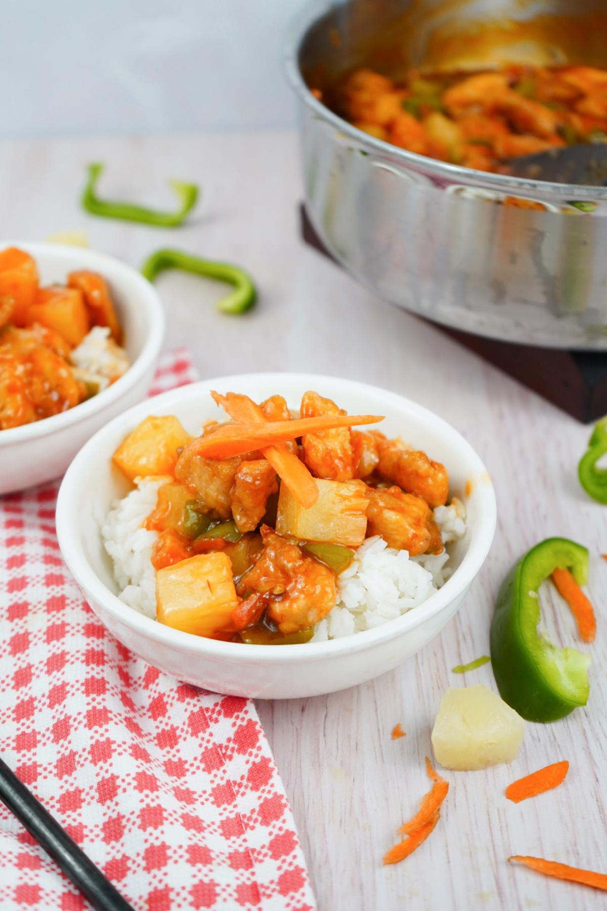 Tangy sweet and sour chicken with pineapple served in a white bowl over fluffy rice. Tangy sweet and sour chicken with pineapple served in a white bowl over fluffy rice.
