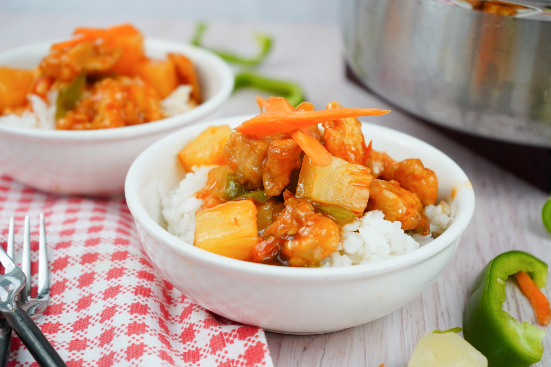 Close-up of sweet and sour chicken with carrots, bell peppers, and pineapple chunks on rice.