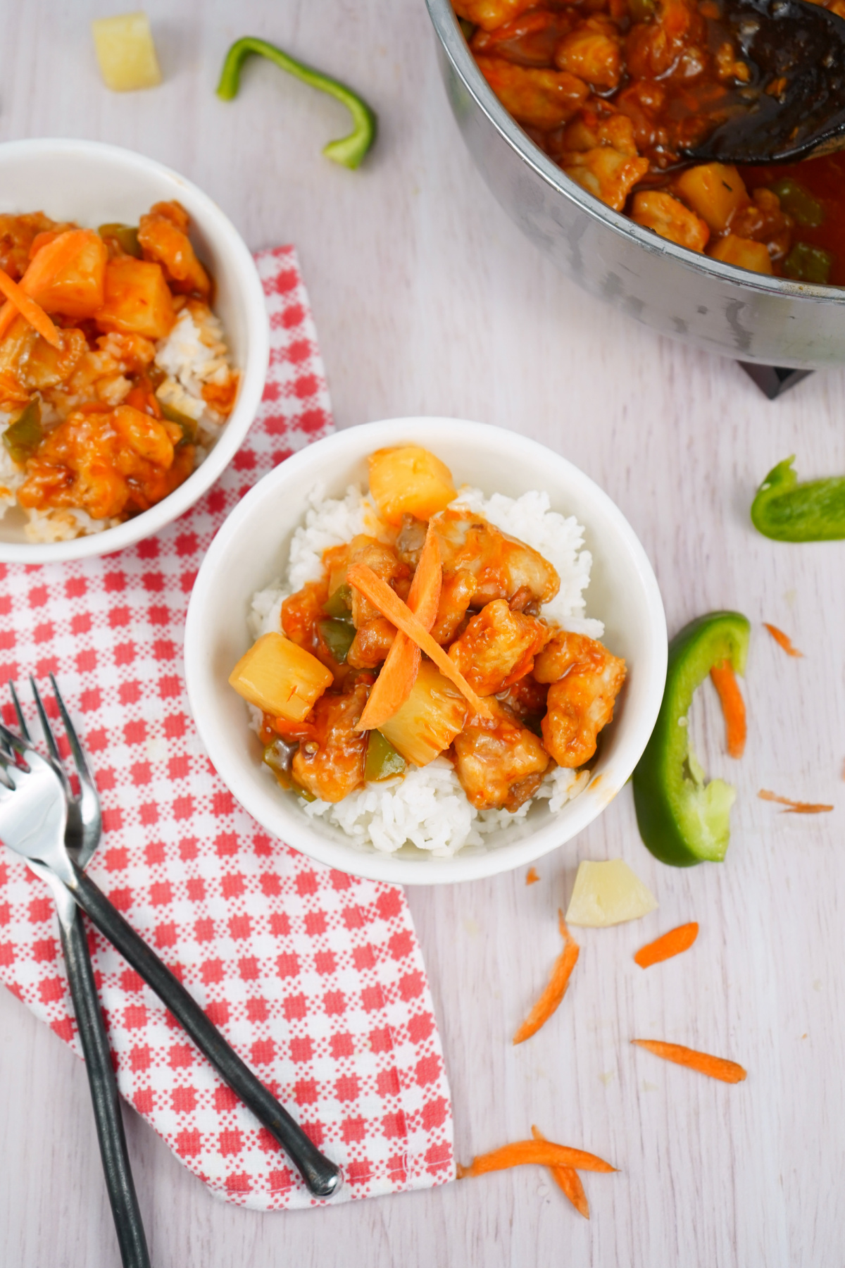 Colorful sweet and sour chicken with vegetables and pineapple in a serving bowl with rice.