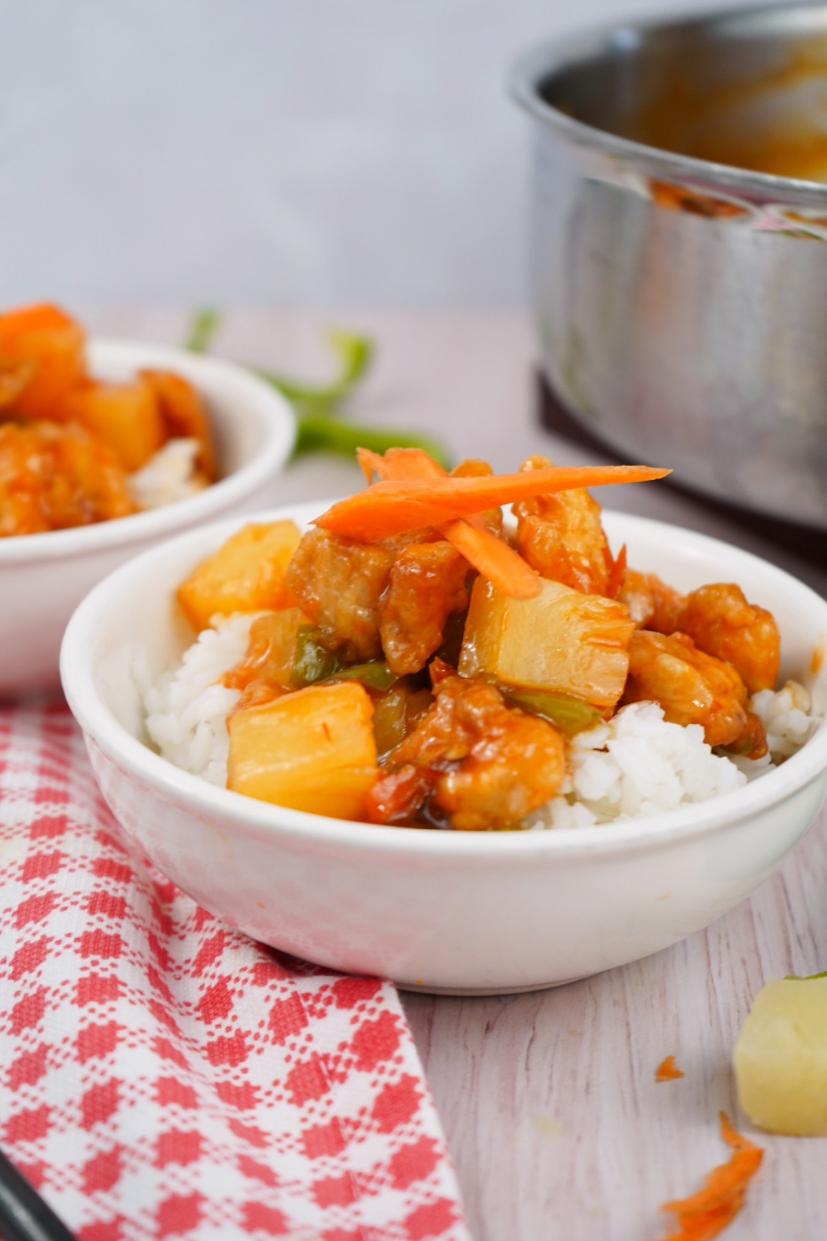 Skillet-to-bowl sweet and sour chicken with sauce poured over rice in a white dish.