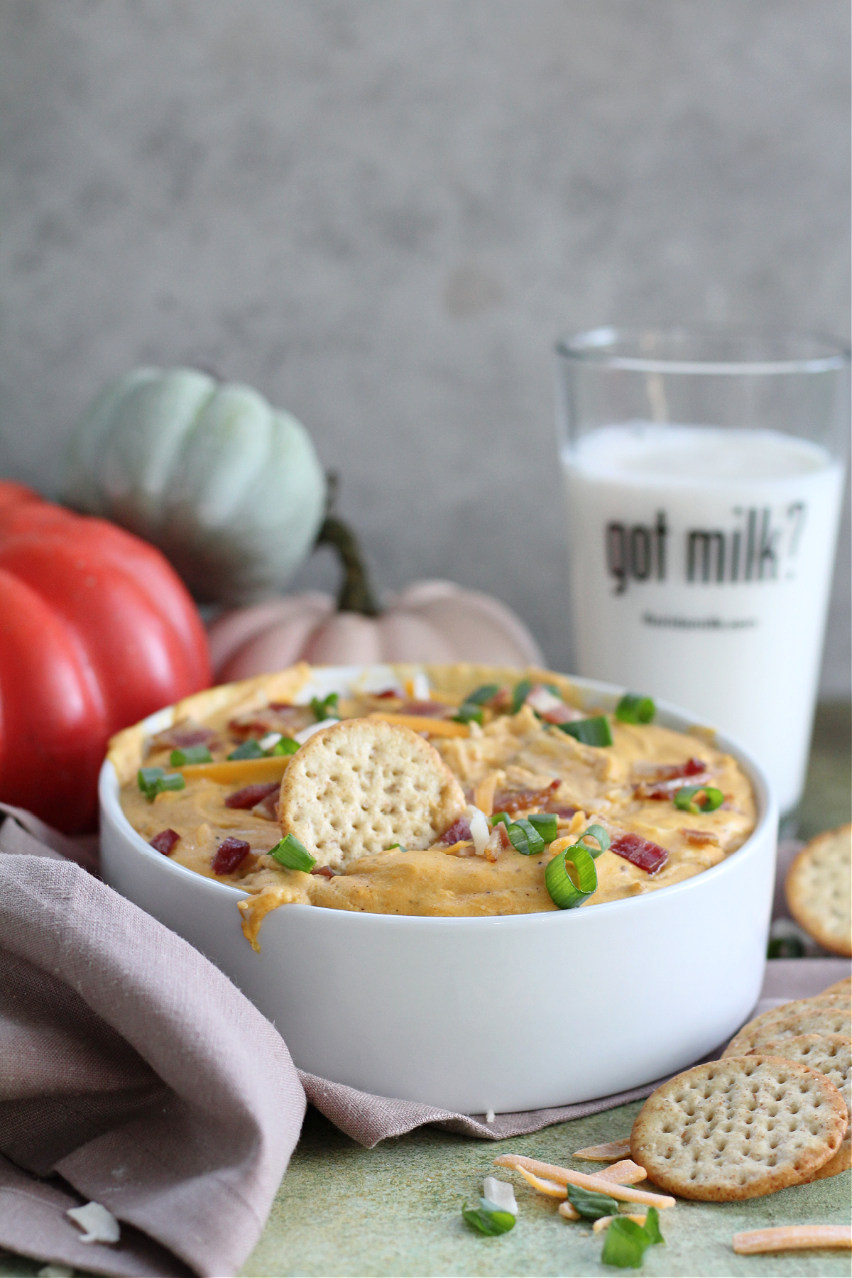 Easy Pumpkin and Bacon Dip Appetizer Pumpkin and Bacon Dip served warm in a white baking dish topped with chopped green onions and bacon