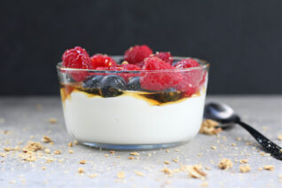 Bowl of yogurt mixed with protein powder topped with berries and granola.