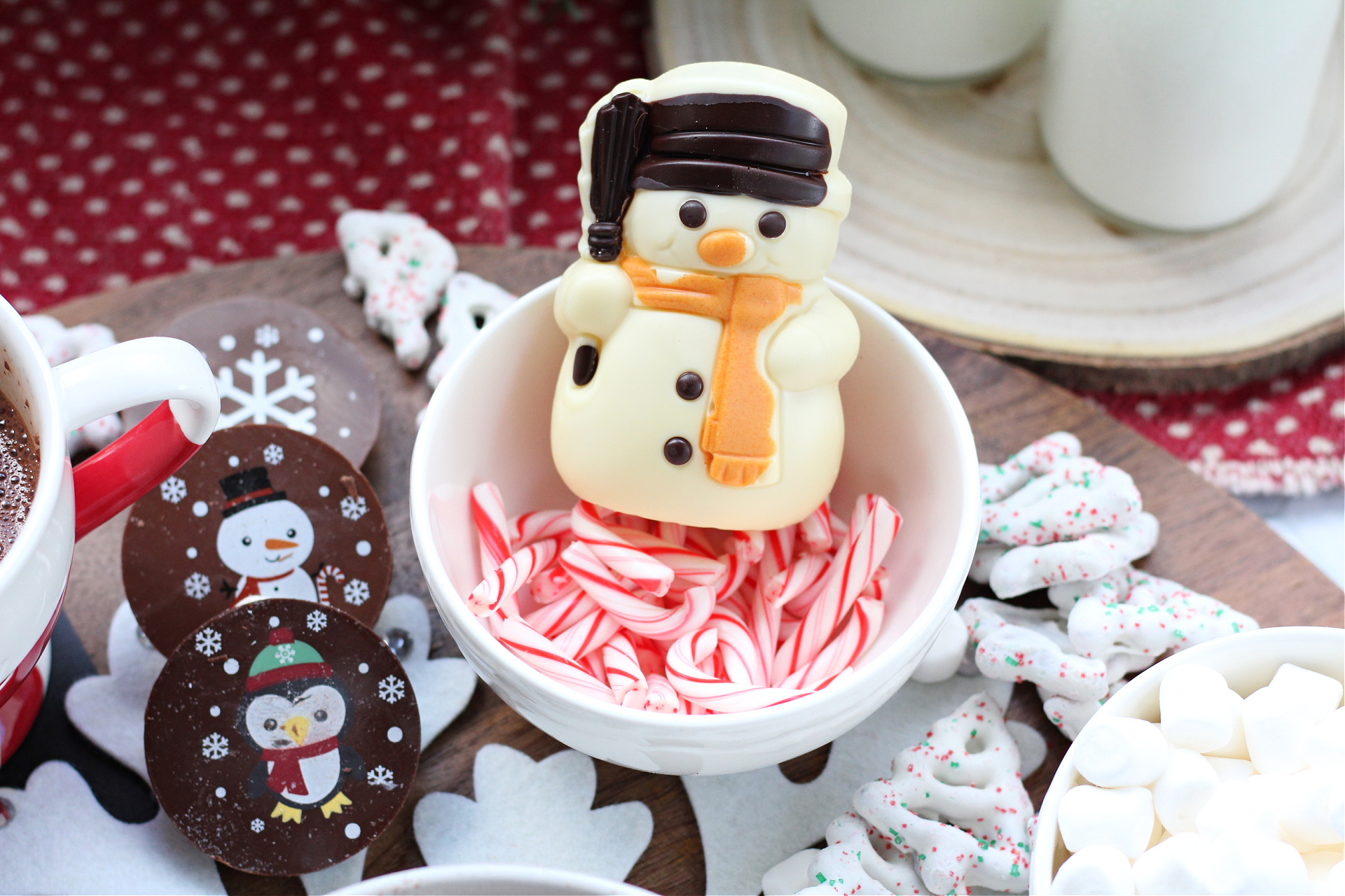Close-up of a hot cocoa bomb on a peppermint hot cocoa board with mini candy canes.