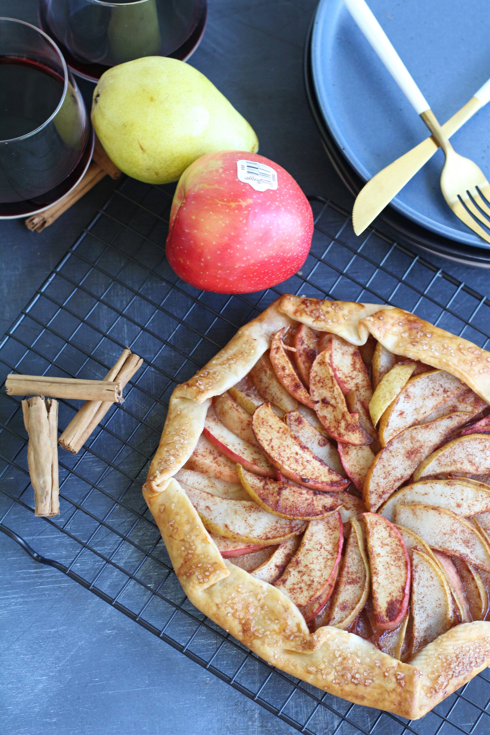 Red wine ad fresh fruit displayed next to a perfectly browned rustic fruit galette.