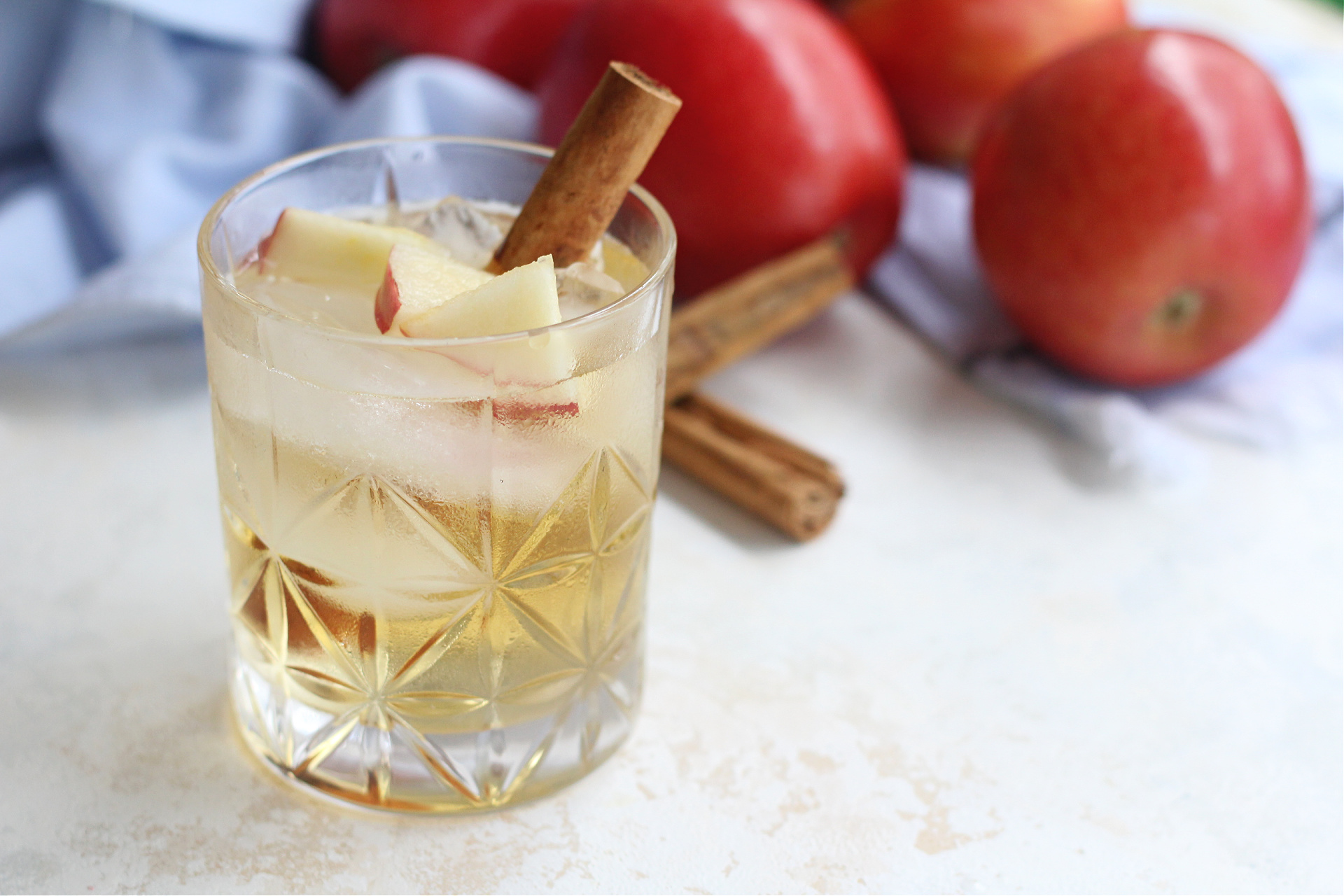 Refreshing apple sangria served over ice in a cocktail glass with fruit garnish.