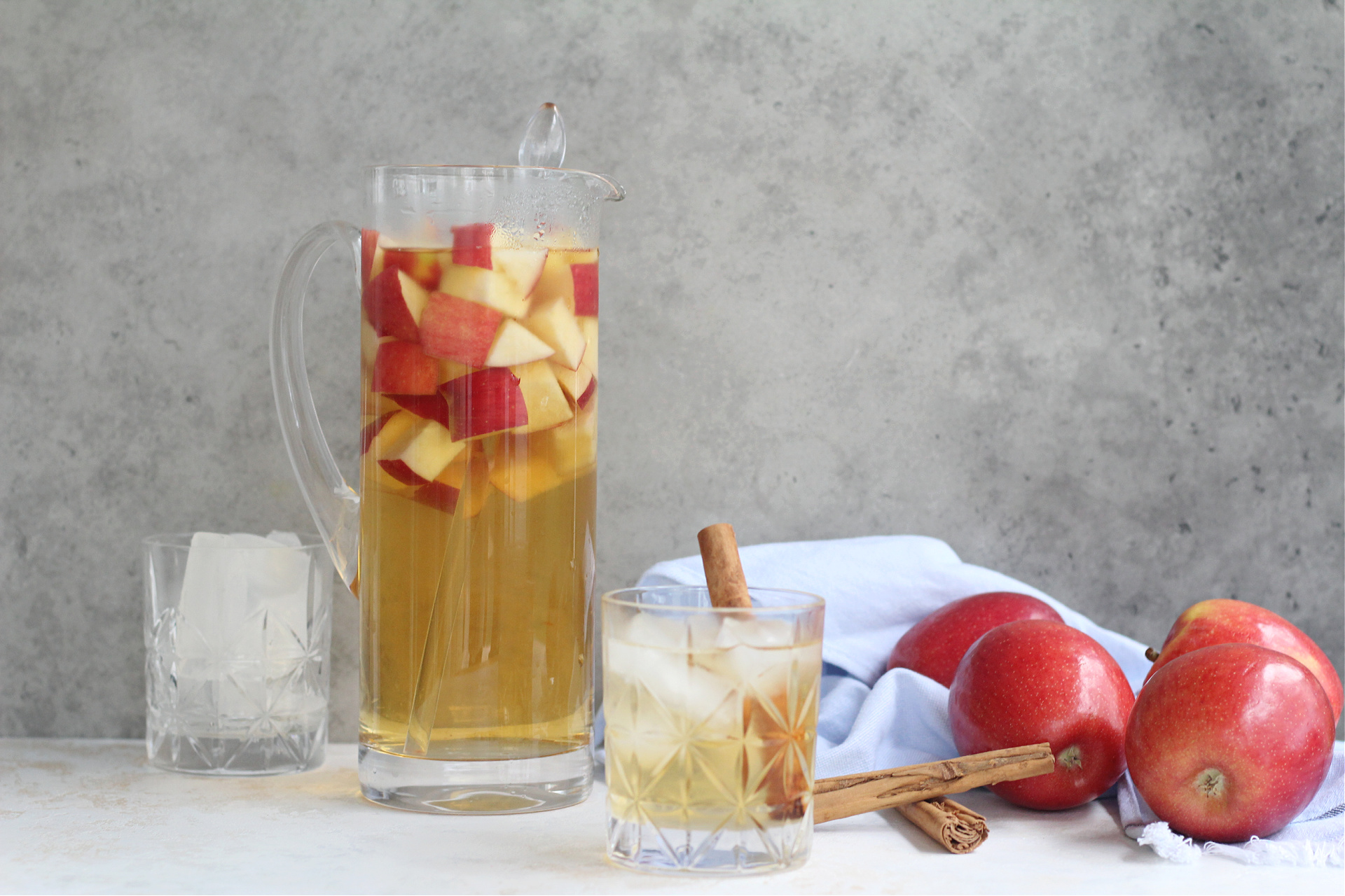 Festive glass of homemade apple sangria over ice with colorful fruit inside.