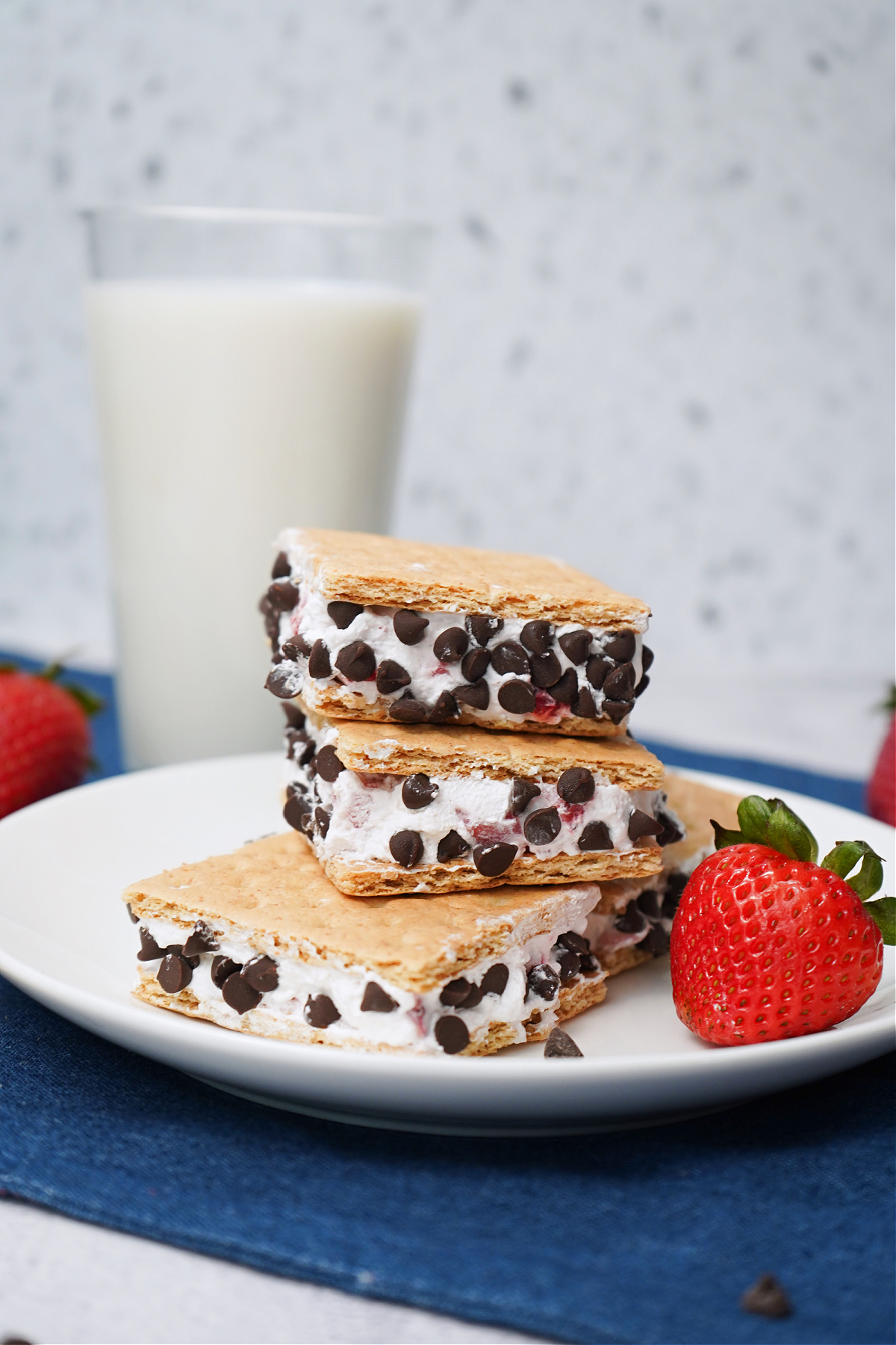 Frozen Cool Whip ice cream sandwiches with strawberries and chocolate chips on a white plate.