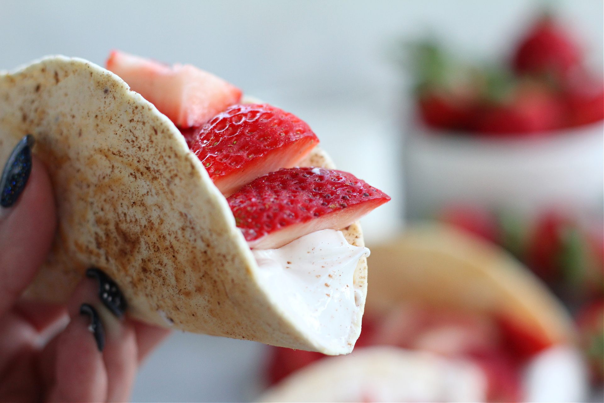 Close-up of strawberry cheesecake–style tacos topped with fresh sliced strawberries