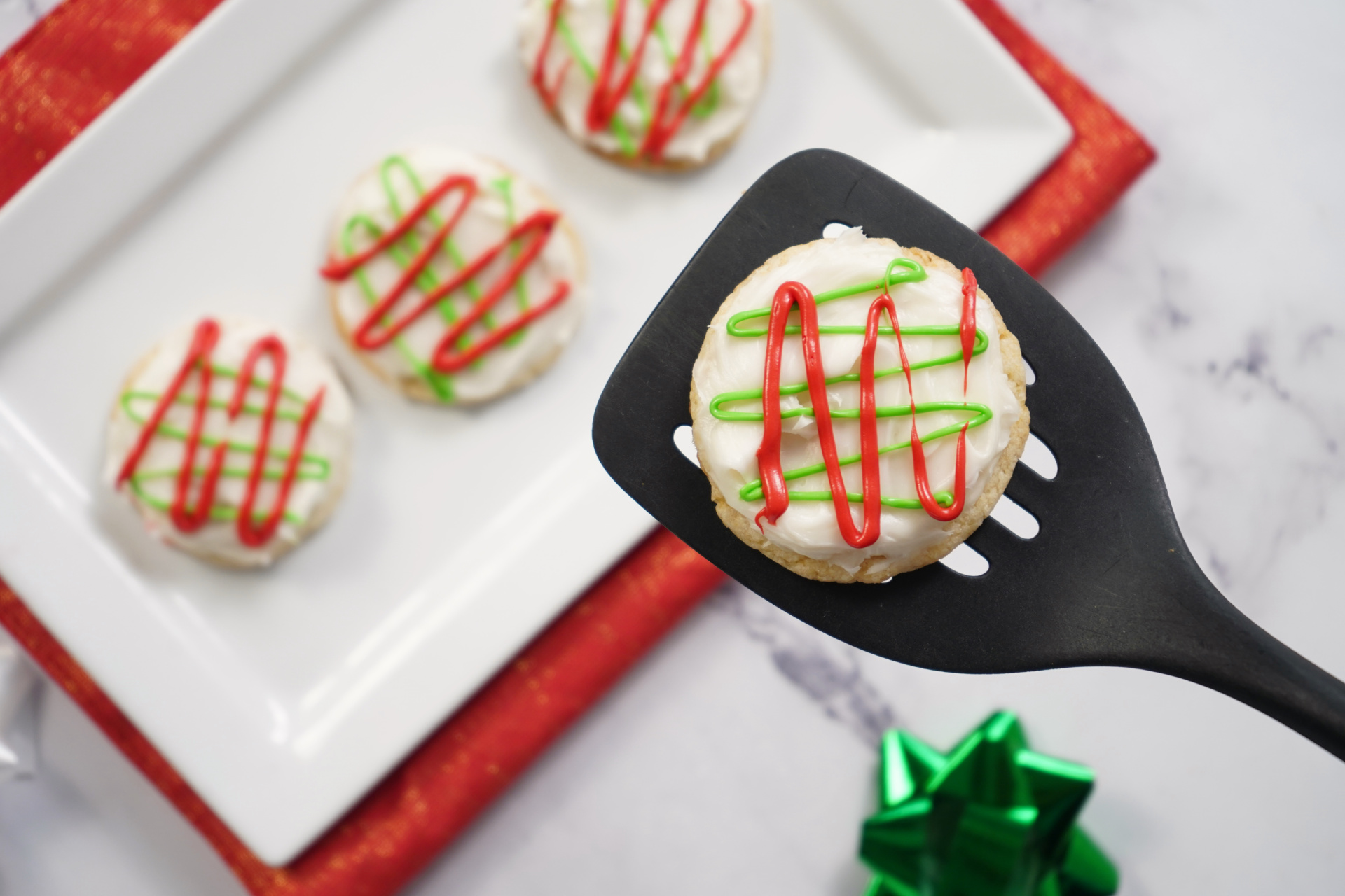 Christmas sugar cookie lifted with a spatula, decorated with holiday-colored icing