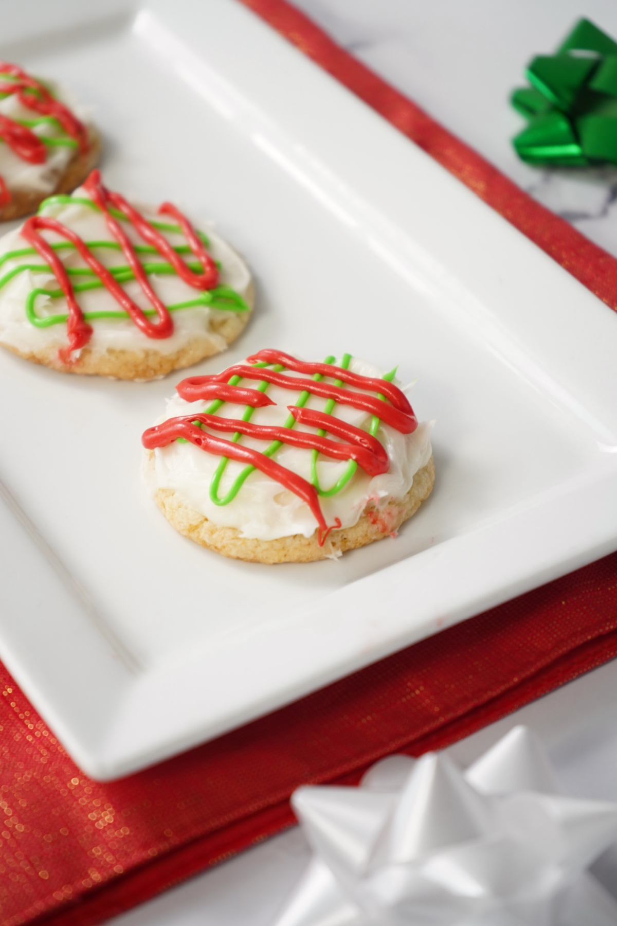 Soft Christmas sugar cookie with white frosting and festive red and green drizzle