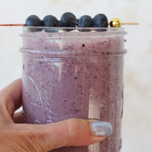 Beet blueberry smoothie in a mason jar with fresh blueberries