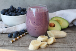 Homemade blueberry avocado smoothie with fresh ingredients on a table