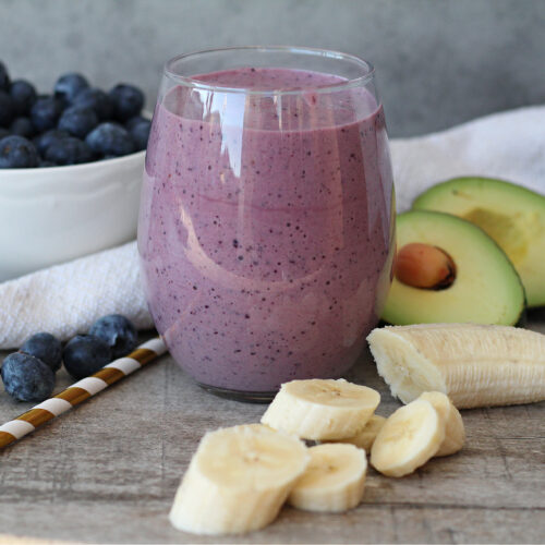 Homemade blueberry avocado smoothie with fresh ingredients on a table