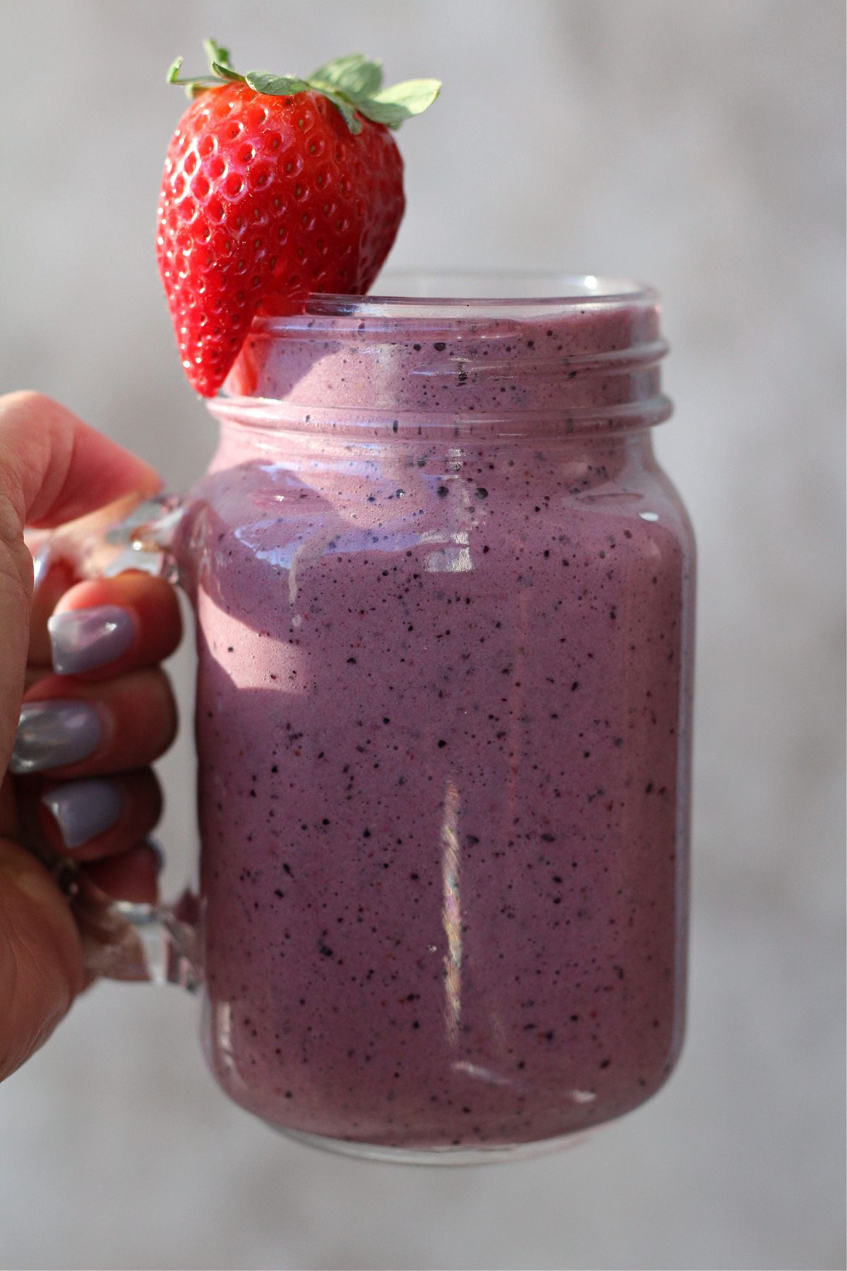 Carrot blueberry smoothie with greens in a glass mason jar