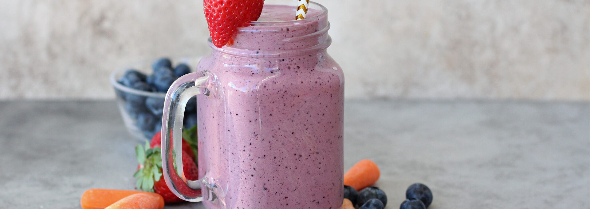 Fresh carrot blueberry smoothie topped with a strawberry