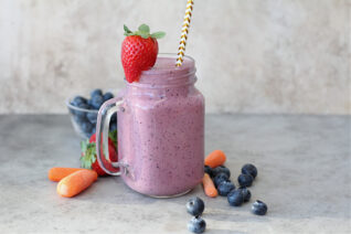 Fresh carrot blueberry smoothie topped with a strawberry