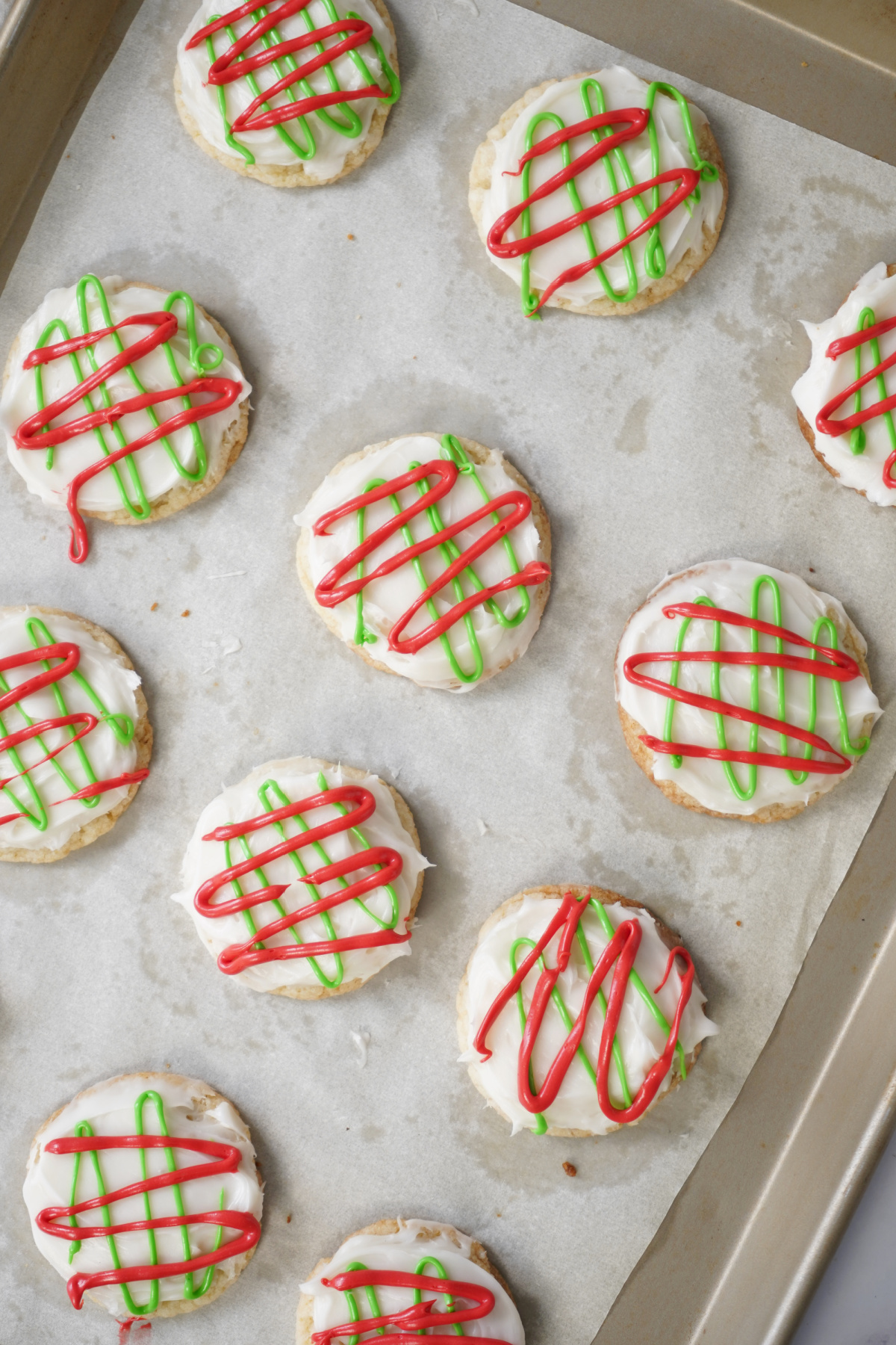 Easy Christmas sugar cookies decorated for the holidays on a baking sheet with parchment paper