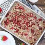 Homemade strawberry oat bars cooling after baking with a glass of milk