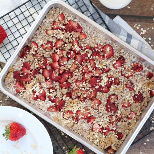 Homemade strawberry oat bars cooling after baking with a glass of milk