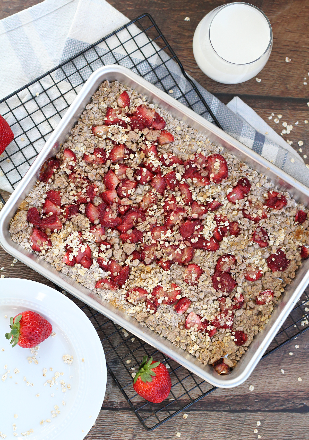 Homemade strawberry oat bars cooling after baking with a glass of milk