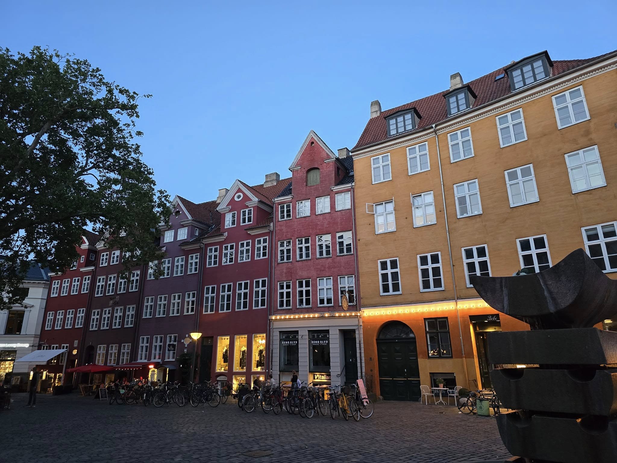 Street view of Copenhagen with bikes, historic buildings, and caf&eacute;s