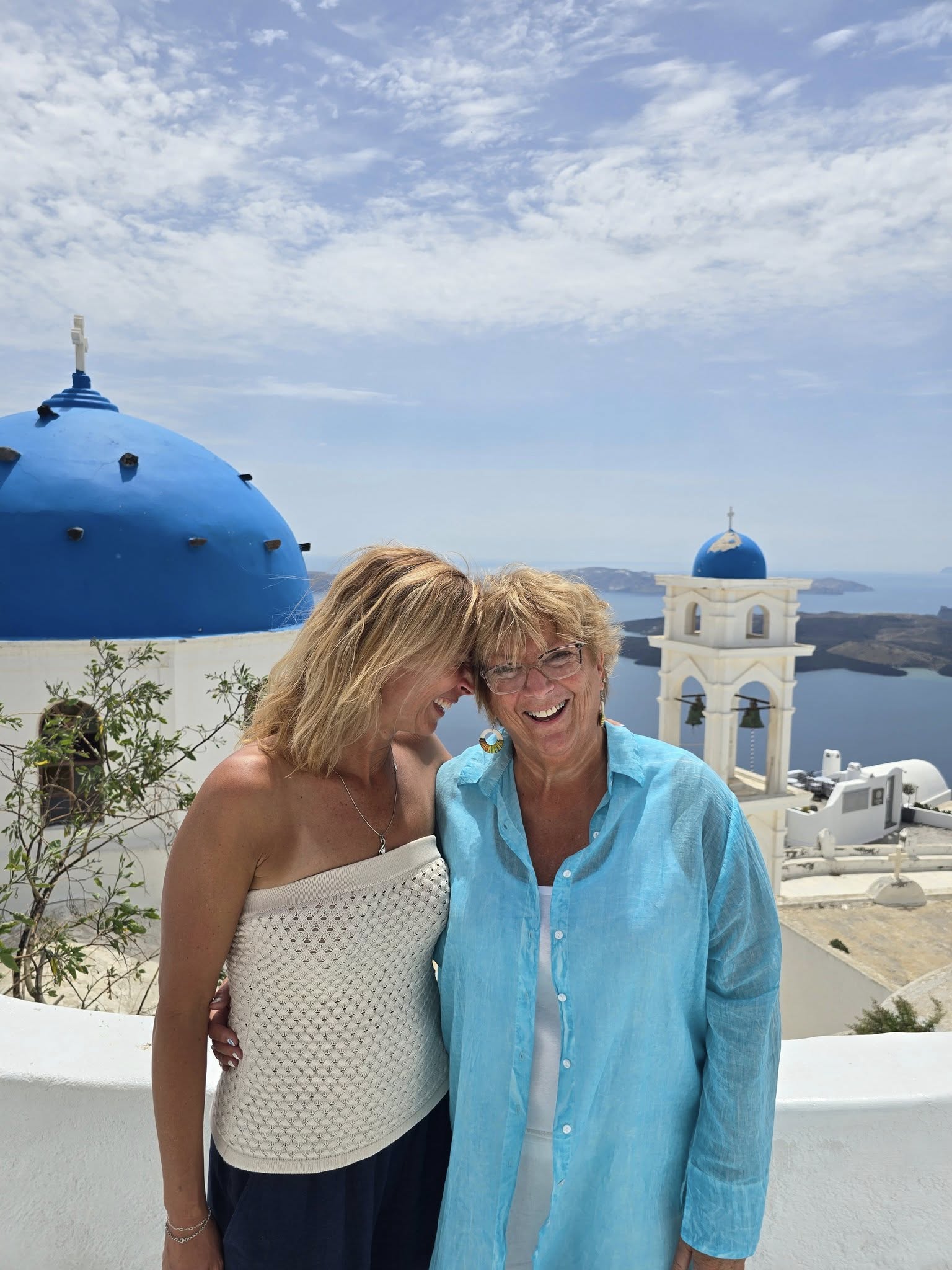 Mom and daughter in front of Blue domed churches and white buildings in Santorini Greece