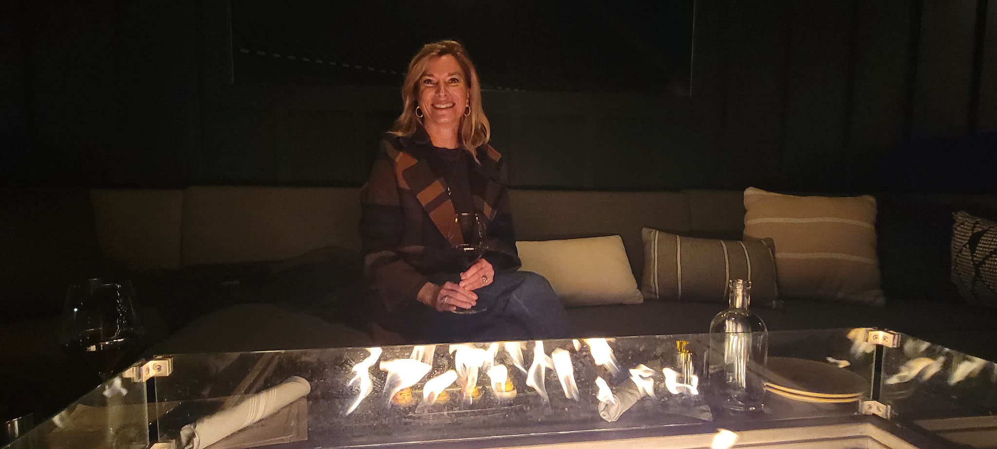 Woman sitting in front of a fire with a glass of wine in Napa