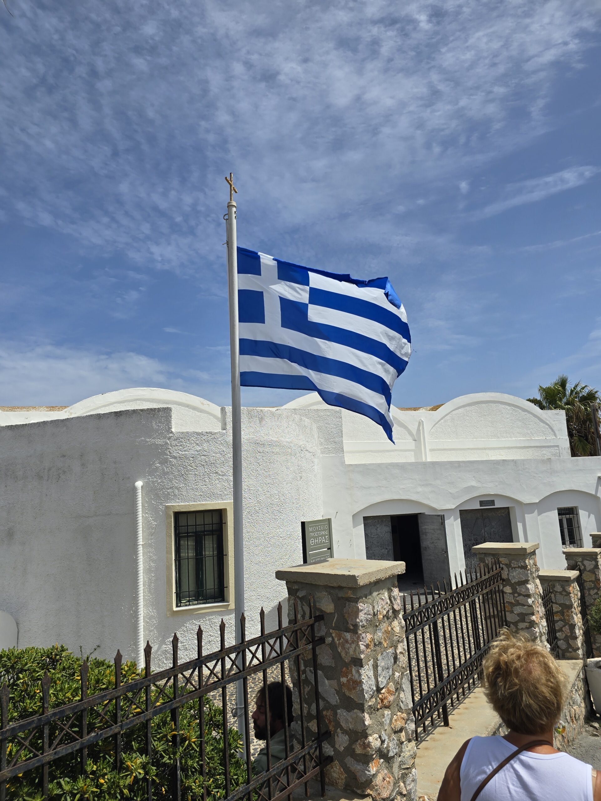greece flag waving in the air in front of a white building