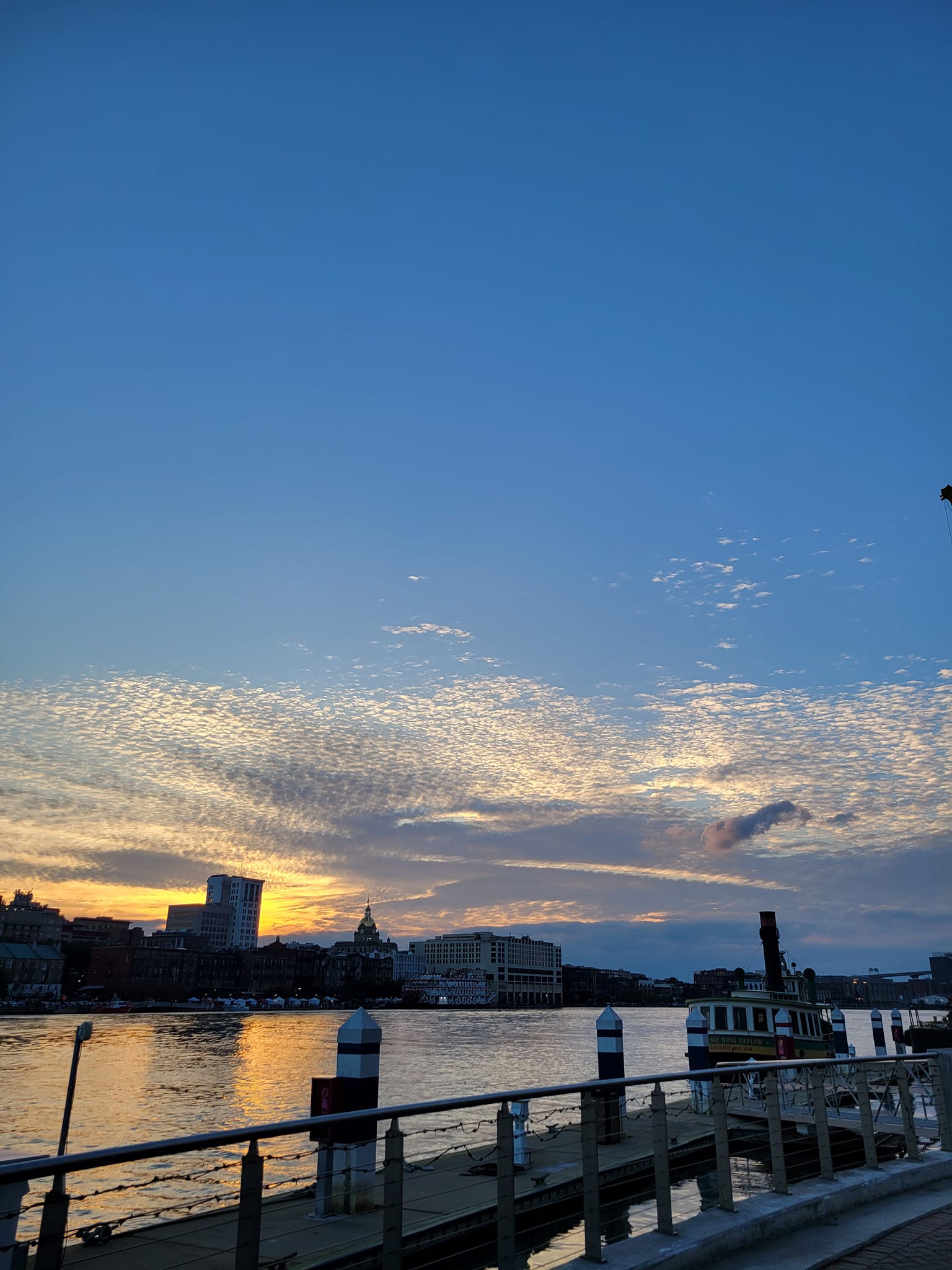Sunset over the Savannah River with colorful skies and historic buildings along River Street.