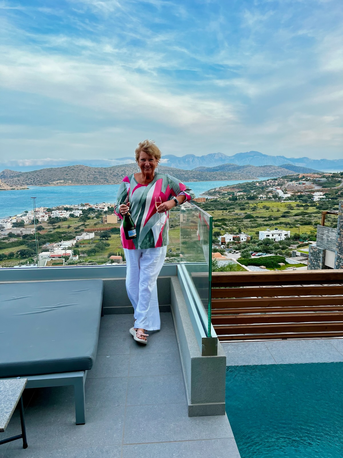 woman on balcony at cayo resort elounda crete with champagne
