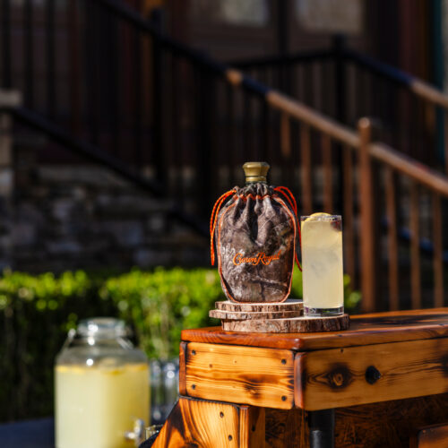The Camo Crown Cooler cocktail served over ice with lemon garnish in a clear glass.