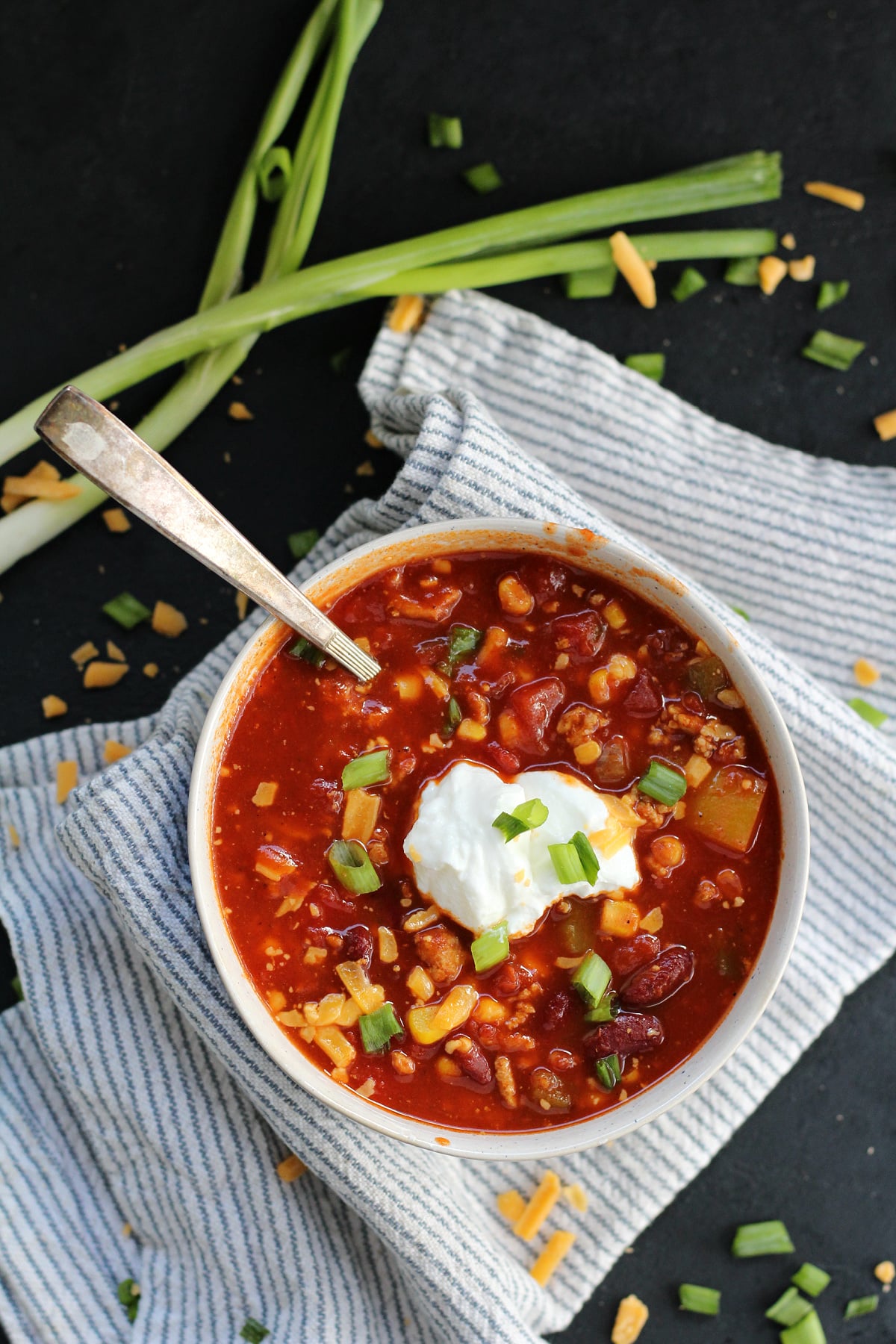 Bowl of homemade turkey chili topped with shredded cheese and green onions