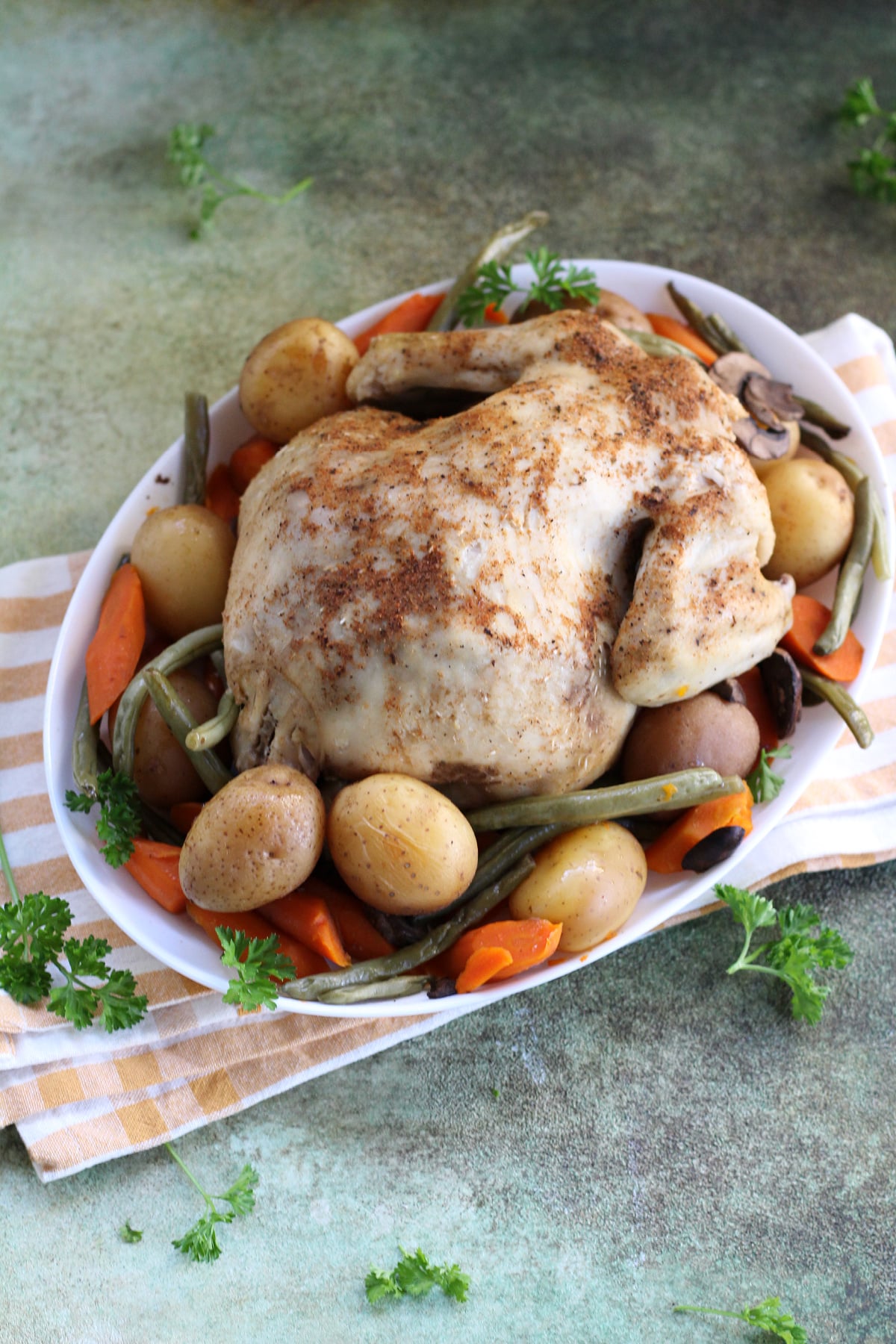Tender slow cooker roasted chicken served with carrots, potatoes, and green beans